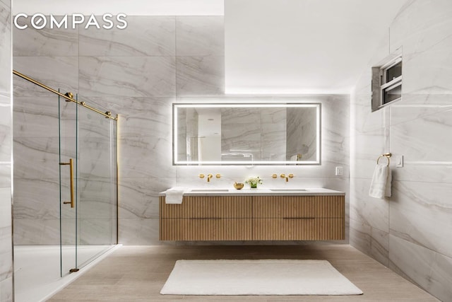 63 Greene St Unit 2D, New York City, NY 10012 - bathroom featuring double vanity, a marble finish shower, and tile walls