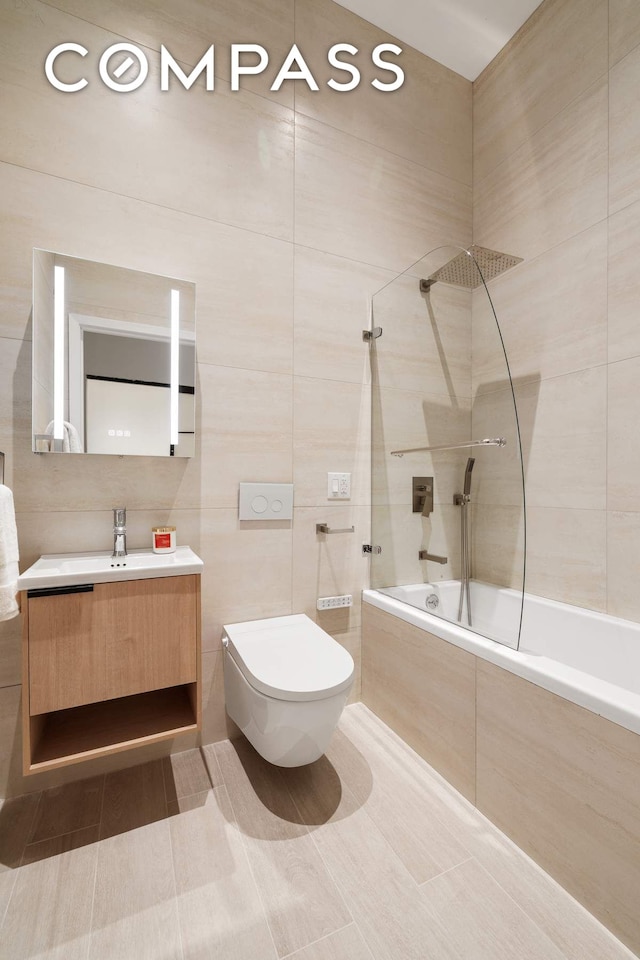 63 Greene St Unit 2D, New York City, NY 10012 - full bath featuring tiled shower / bath combo, tile walls, vanity, and toilet