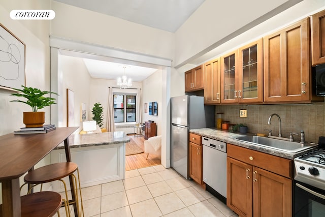62 E 87th St Unit 1B, New York City, NY 10128 - kitchen featuring dishwashing machine, a sink, brown cabinets, gas stove, and a chandelier