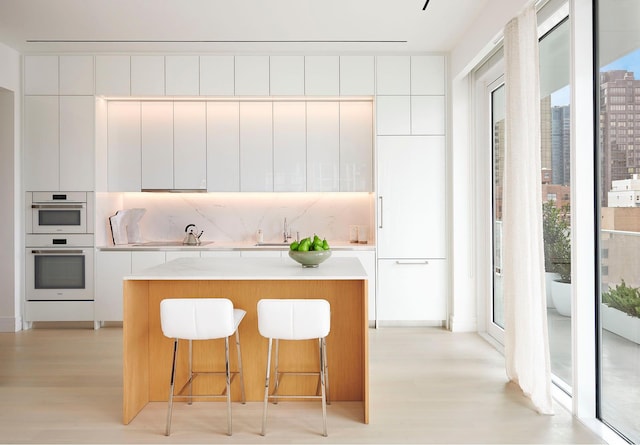200 E 59th St Unit 15A, New York City, NY 10022 - kitchen with modern cabinets, light wood finished floors, white double oven, a center island, and a sink