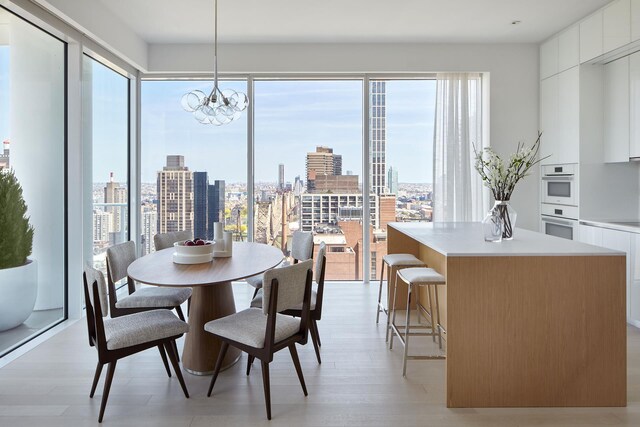 200 E 59th St Unit 26D, New York City, NY 10022 - dining room with a chandelier, a city view, and light wood-style flooring