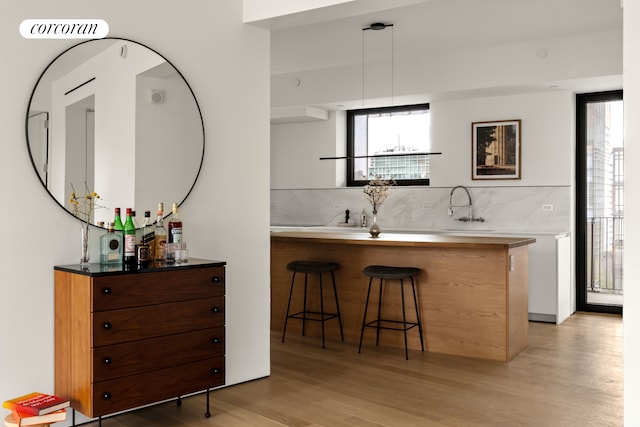 9 Chapel St Unit 9A, New York City, NY 11201 - bar featuring light wood-style flooring, tasteful backsplash, a sink, and pendant lighting