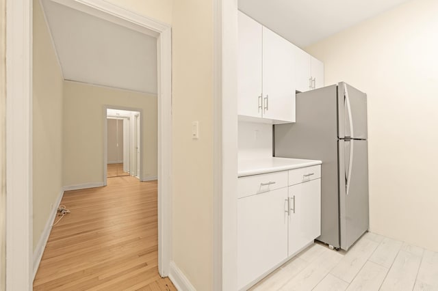 34-21 78th St Unit 1-H, New York City, NY 11372 - kitchen with light wood-type flooring, white cabinets, light countertops, and freestanding refrigerator