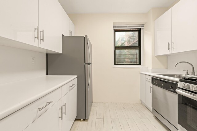 34-21 78th St Unit 1-H, New York City, NY 11372 - kitchen with appliances with stainless steel finishes, light countertops, white cabinets, and light wood-style floors