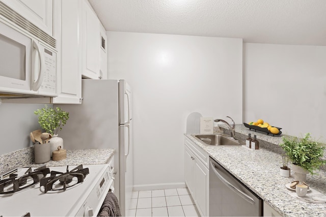 5 E 22nd St Unit 3F, New York City, NY 10010 - kitchen featuring white appliances, a sink, light tile patterned floors, white cabinetry, and light stone counters