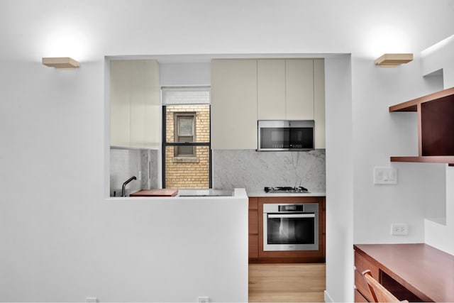 253 W 16th St Unit 6D, New York City, NY 10011 - kitchen with stainless steel appliances, backsplash, open shelves, light wood finished floors, and gray cabinets