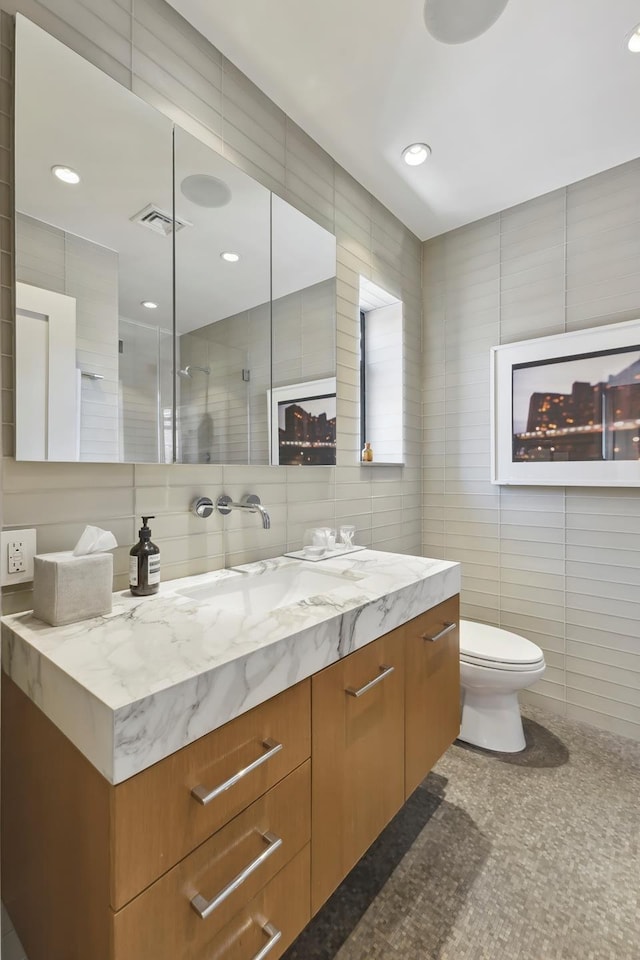 465 W 23rd St Unit 19D, New York City, NY 10011 - bathroom with vanity, tile walls, toilet, a shower with shower door, and recessed lighting