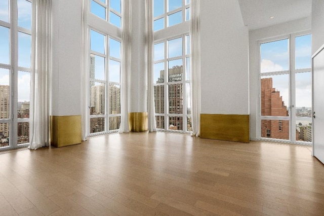 305 E 51st St Unit 20-B, New York City, NY 10022 - spare room with a high ceiling, healthy amount of natural light, wood finished floors, and a view of city