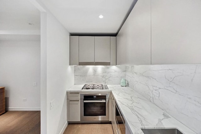 305 E 51st St Unit 20-B, New York City, NY 10022 - kitchen with appliances with stainless steel finishes, modern cabinets, decorative backsplash, and light stone counters