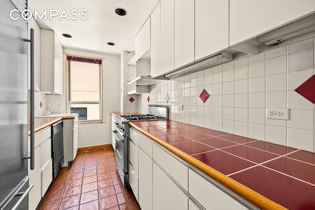 345 W 55th St Unit 8Ab, New York City, NY 10019 - kitchen featuring high quality appliances, white cabinetry, backsplash, and a sink