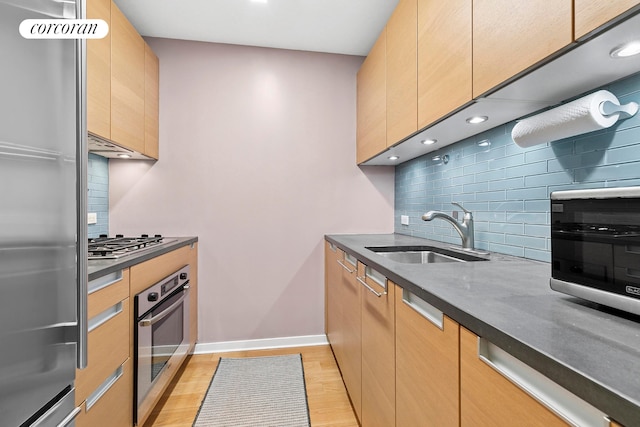 310 W 52nd St Unit 15A, New York City, NY 10019 - kitchen with appliances with stainless steel finishes, a sink, decorative backsplash, light wood-style flooring, and recessed lighting