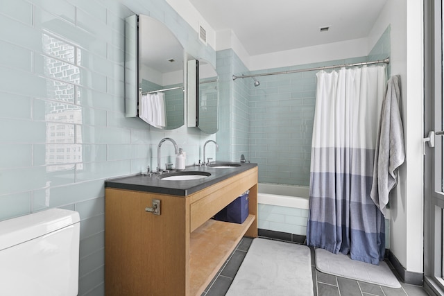 310 W 52nd St Unit 15A, New York City, NY 10019 - full bathroom featuring tile patterned flooring, double vanity, tiled shower / bath, toilet, and tile walls