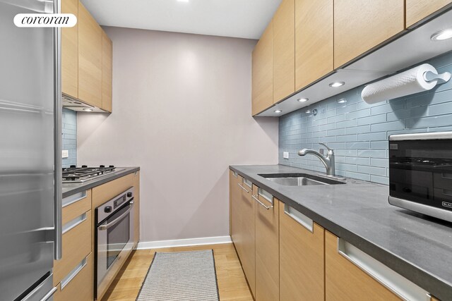 310 W 52nd St Unit 15A, New York City, NY 10019 - kitchen with stainless steel appliances, a sink, backsplash, light wood-style floors, and recessed lighting
