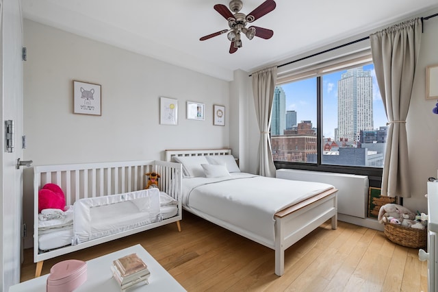 10-55 47th Ave Unit 7-F, New York City, NY 11101 - bedroom with wood finished floors, a skyline view, and a ceiling fan