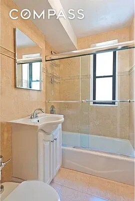 30 E 9th St Unit 2Ii, New York City, NY 10003 - full bath featuring toilet, vanity, shower / bath combination with glass door, and tile patterned flooring