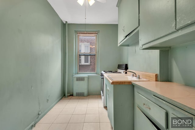 3321 Bruckner Blvd Unit 2D, New York City, NY 10461 - kitchen with radiator, white range with gas stovetop, light countertops, ceiling fan, and light tile patterned floors