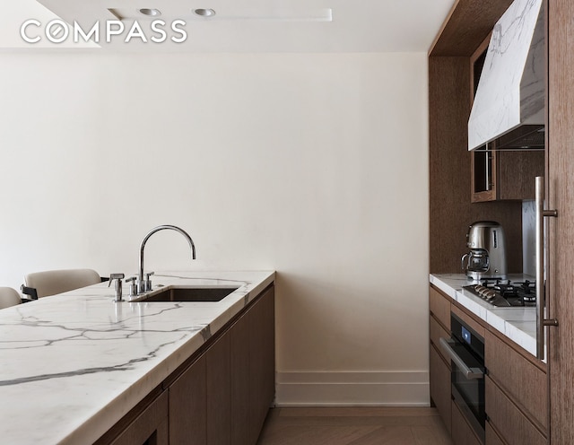 40 Bleecker St Unit 3E, New York City, NY 10012 - kitchen featuring range hood, oven, a sink, stainless steel gas stovetop, and baseboards