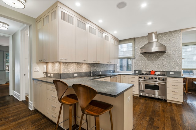 14 E 75th St Unit 10D, New York City, NY 10021 - kitchen with appliances with stainless steel finishes, wall chimney exhaust hood, a sink, dark countertops, and dark wood-style flooring