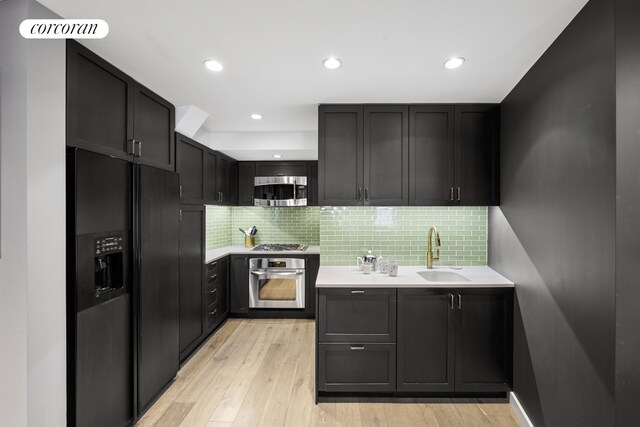 2166 Broadway Unit 7B, New York City, NY 10024 - kitchen featuring appliances with stainless steel finishes, light countertops, light wood-type flooring, decorative backsplash, and dark cabinets