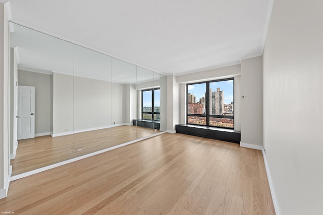 530 E 76th St Unit 18G, New York City, NY 10021 - empty room featuring light wood-style flooring, baseboards, ornamental molding, and a view of city