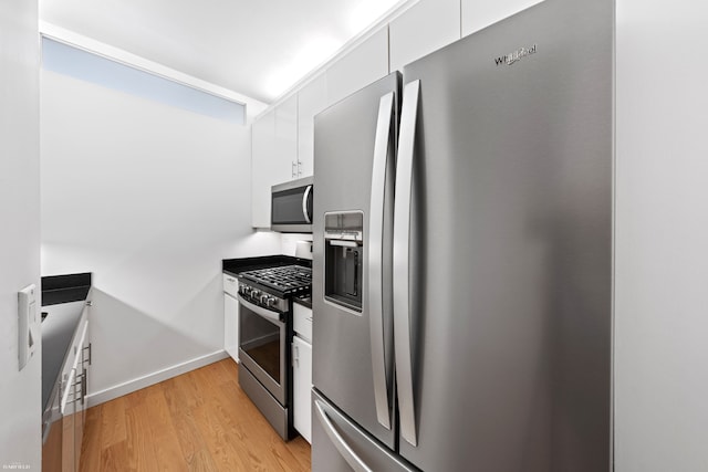 530 E 76th St Unit 18G, New York City, NY 10021 - kitchen with stainless steel appliances, white cabinets, light wood-style floors, and baseboards