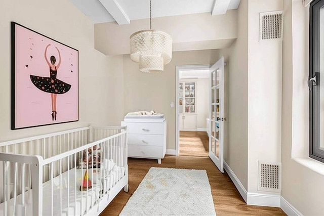 400 W End Ave Unit 6B, New York City, NY 10024 - bedroom featuring a chandelier, wood finished floors, beamed ceiling, baseboards, and a crib