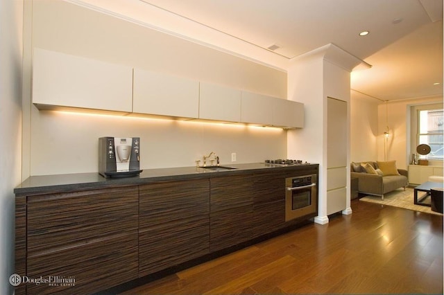 55 Wall St Unit 816, New York City, NY 10005 - kitchen featuring appliances with stainless steel finishes, a sink, dark wood finished floors, dark countertops, and recessed lighting
