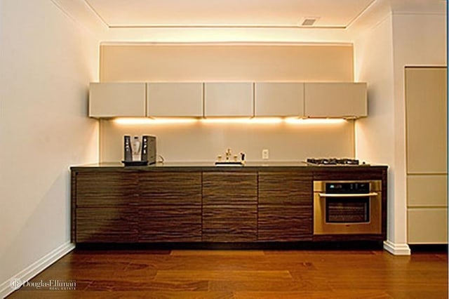 55 Wall St Unit 816, New York City, NY 10005 - kitchen with stainless steel oven, dark wood-style floors, baseboards, gas cooktop, and a sink