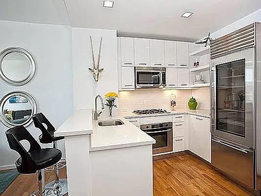 635 W 42nd St Unit 12M, New York City, NY 10036 - kitchen with appliances with stainless steel finishes, a peninsula, open shelves, white cabinets, and dark wood-style floors