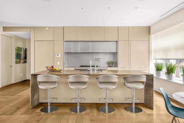 21 W 20th St Unit Ph1, New York City, NY 10011 - kitchen featuring a large island, modern cabinets, light stone counters, a kitchen bar, and cream cabinetry