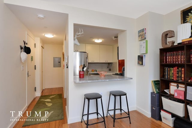 303 W 146th St Unit 7-R, New York City, NY 10039 - kitchen with freestanding refrigerator, light wood-style floors, electric panel, and decorative backsplash