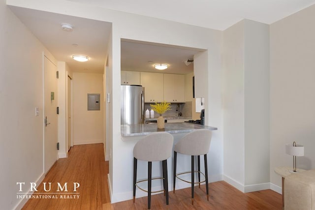 303 W 146th St Unit 7-R, New York City, NY 10039 - kitchen featuring freestanding refrigerator, electric panel, light wood-style flooring, tasteful backsplash, and a peninsula