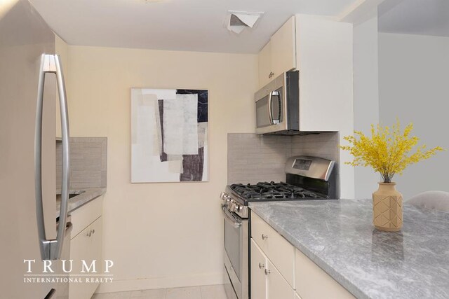 303 W 146th St Unit 7-R, New York City, NY 10039 - kitchen with stainless steel appliances, decorative backsplash, white cabinets, and light countertops