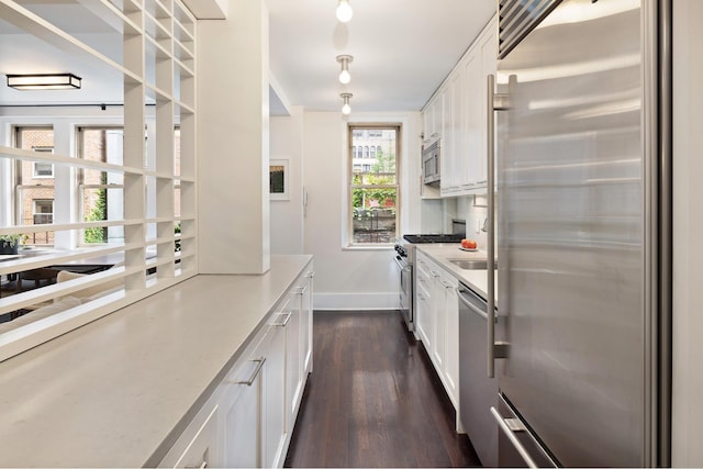 59 W 12th St Unit 4A, New York City, NY 10011 - kitchen with high quality appliances, dark wood-type flooring, baseboards, white cabinetry, and light countertops
