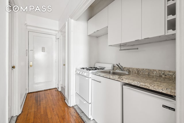 433 W 34th St Unit 8D, New York City, NY 10001 - kitchen with white range with gas stovetop, fridge, white cabinets, hardwood / wood-style floors, and glass insert cabinets