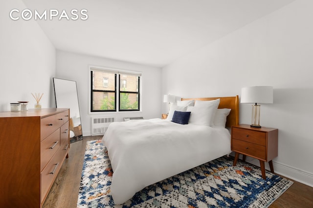 140 7th Ave Unit 4M, New York City, NY 10011 - bedroom featuring radiator heating unit, wood finished floors, and baseboards