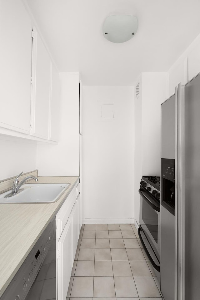 77 7th Ave Unit 9T, New York City, NY 10011 - kitchen featuring stainless steel appliances, a sink, white cabinetry, light countertops, and light tile patterned floors