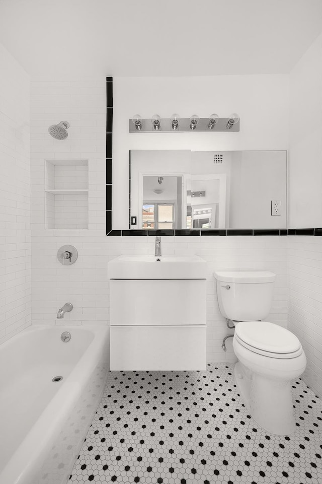 77 7th Ave Unit 9T, New York City, NY 10011 - bathroom with tile walls, tile patterned flooring, toilet, vanity, and  shower combination