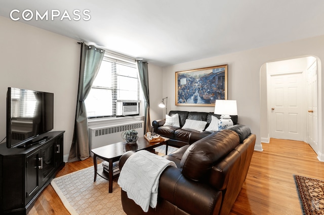 22-40 80th St Unit 3B, New York City, NY 11370 - living area with radiator heating unit, light wood finished floors, arched walkways, cooling unit, and baseboards