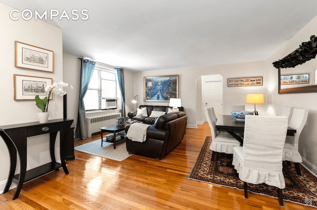 22-40 80th St Unit 3B, New York City, NY 11370 - living room featuring radiator heating unit, arched walkways, light wood-style floors, and baseboards