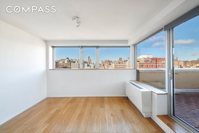 2280 Frederick Douglass Blvd Unit 11E, New York City, NY 10027 - spare room featuring wood finished floors, a city view, and baseboards