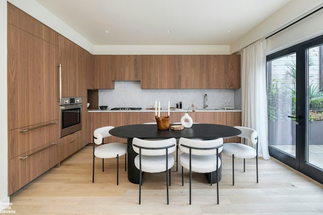353 20th St Unit Th, New York City, NY 11215 - kitchen with stainless steel oven, modern cabinets, tasteful backsplash, brown cabinetry, and light wood-style flooring