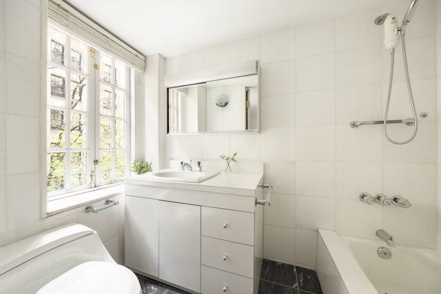 27 W 67th St Unit 2Fe, New York City, NY 10023 - bathroom featuring tile walls, vanity, plenty of natural light, shower / tub combination, and toilet