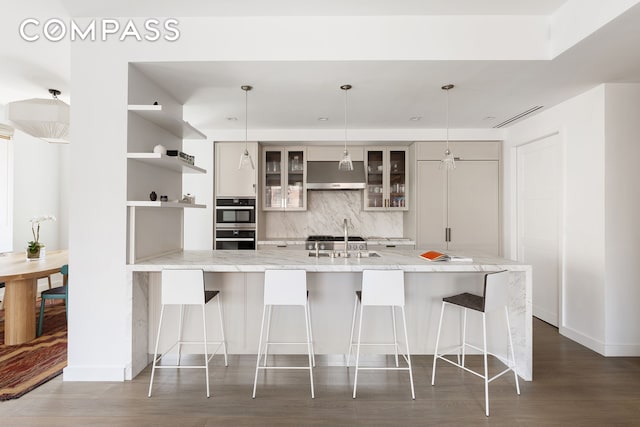 116 University Pl Unit 5, New York City, NY 10003 - kitchen featuring under cabinet range hood, backsplash, a sink, open shelves, and a breakfast bar area