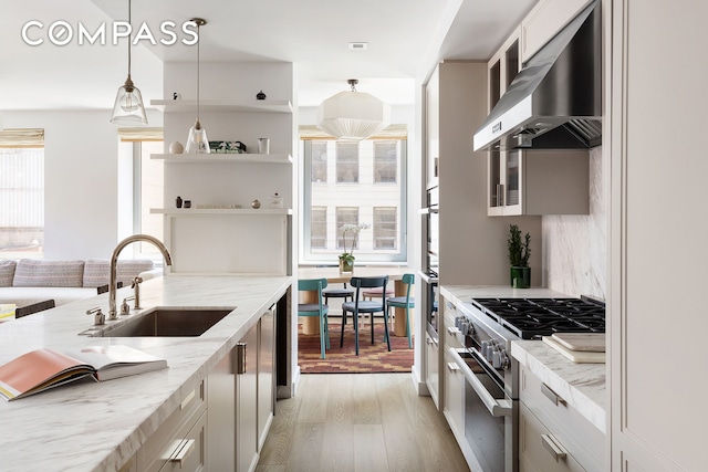 116 University Pl Unit 5, New York City, NY 10003 - kitchen featuring high end stainless steel range, under cabinet range hood, a sink, light wood-style flooring, and light stone counters