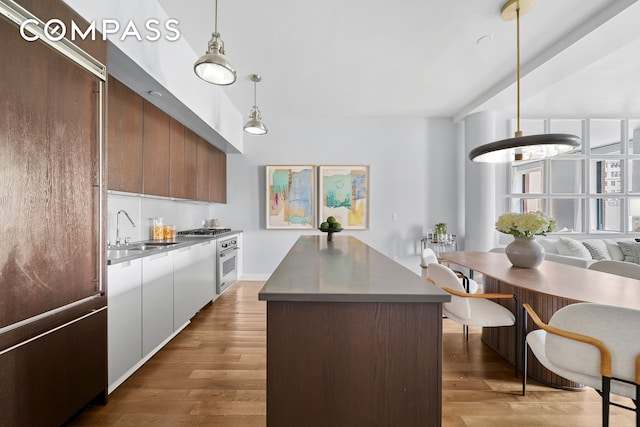 225 5th Ave Unit 7K, New York City, NY 10010 - kitchen with stainless steel appliances, a sink, modern cabinets, wood finished floors, and hanging light fixtures