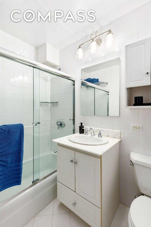 444 E 86th St Unit 11H, New York City, NY 10028 - full bath featuring combined bath / shower with glass door, vanity, tile patterned flooring, and tile walls
