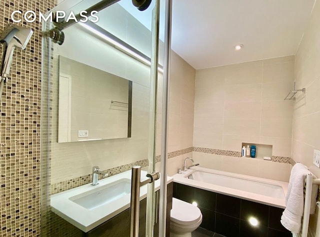 404 E 76th St Unit 30A, New York City, NY 10021 - full bath featuring tile walls, tiled shower, toilet, a relaxing tiled tub, and vanity