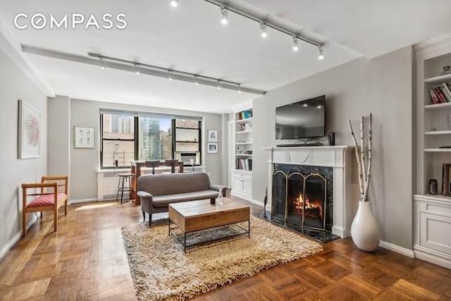 235 E 73rd St Unit 12C, New York City, NY 10021 - living room featuring a fireplace, built in shelves, baseboards, and track lighting