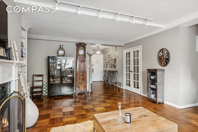 235 E 73rd St Unit 12C, New York City, NY 10021 - unfurnished living room with rail lighting, french doors, a fireplace, and baseboards